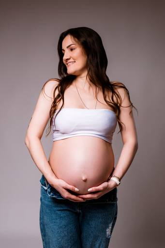 Ensaio gestante em estúdio, barriga a mostra, gestante abraça a barriga