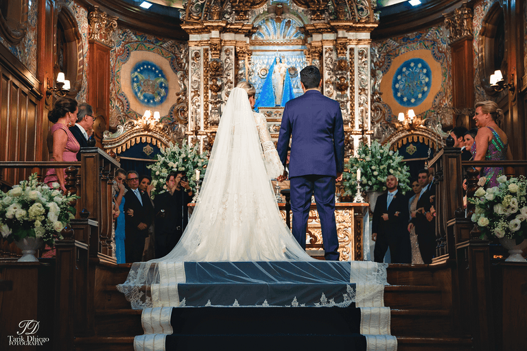 noivos no altar da igreja nossa senhora do brasil, noiva com vestido branco e véu, noivo com traje de noivo, terno azul
