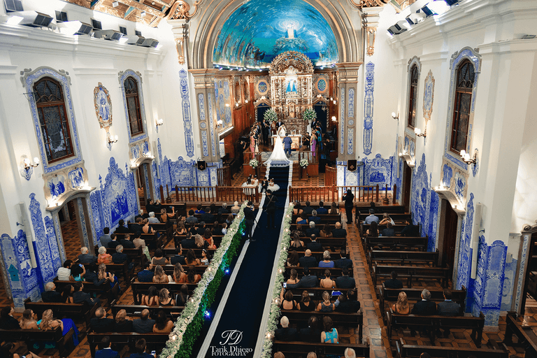 noivos no altar da igreja nossa senhora do brasil, noiva com vestido branco e véu, noivo com traje de noivo, terno azul