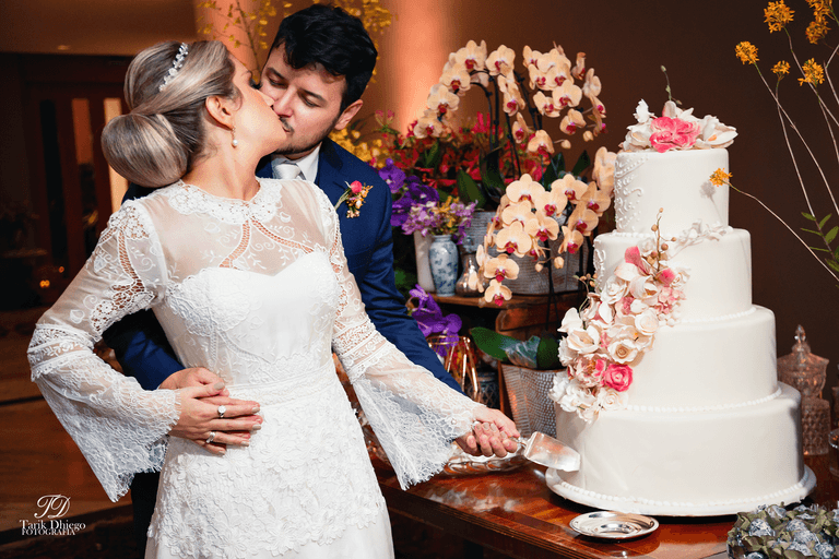 noivos na mesa do bolo no buffet frança no bairro do jardins após a cerimônia do casamento, noiva com vestido de renda branco e noivo com terno azul