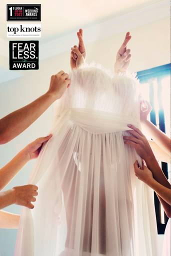 Foto premiada no top Knots, noiva sendo vestida pelas amigas.