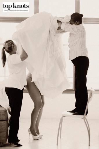 Foto premiada no top knots, foto da noiva colocando o vestido.