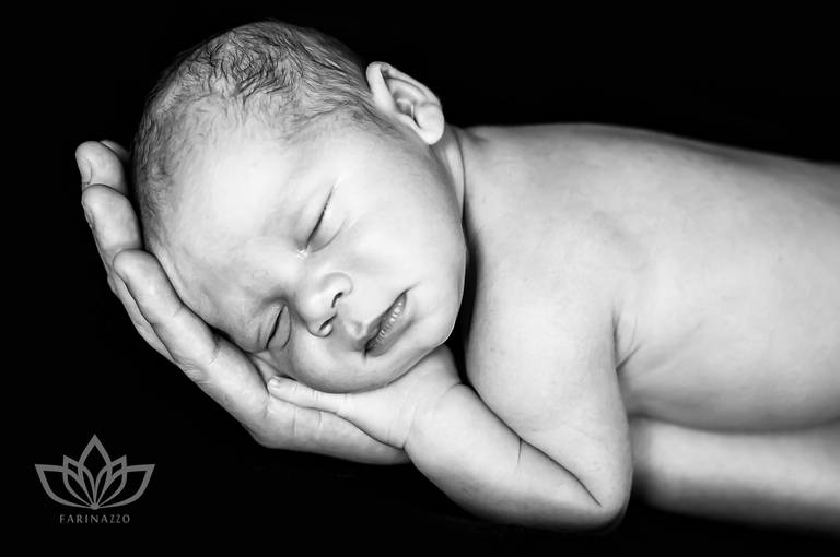 Ensaio Newborn preto e branco com bebê recém nascido deitado na mão do pai.