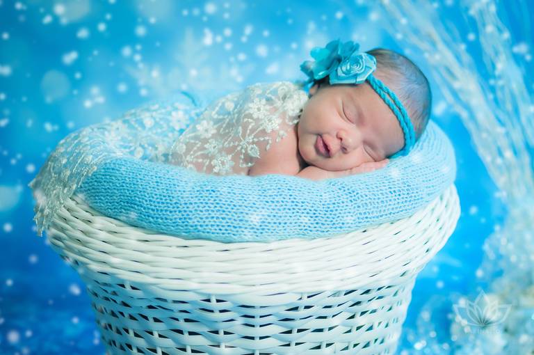 Ensaio Newborn cenário frozen com bebê menina recém nascida dentro de cesto com headband azul newborn.