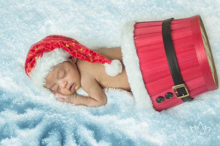 Ensaio Newborn cenário de natal com bebê menino recém nascido caindo do cesto de papai noel.