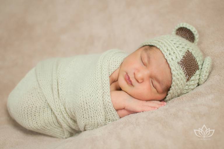 Ensaio Newborn com bebê menino recém nascido enrolado no wrap beje com touca de ratinho.