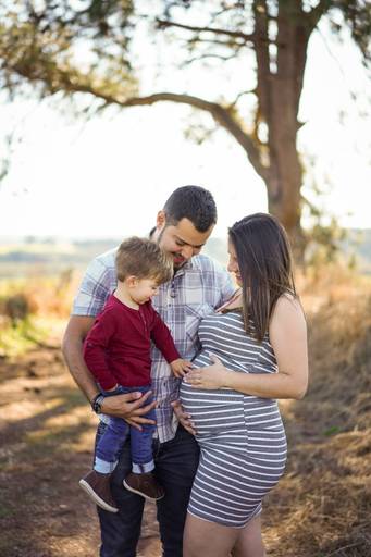 Ensaio gestante life style fotografado pelo melhor fotógrafo de ensaios de campo largo e Curitiba, Michel Druziki. Gestante com filho mais velho com a mão na barriga e marido 