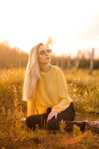 Ensaio fotografado pelo melhor fotógrafo de campo largo e Curitiba, Michel Druziki. Modelo de óculos sentada na grama no por do sol