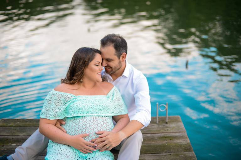 Ensaio de gestante fotografado pelo melhor fotógrafo de ensaios de campo largo e Curitiba. Gestante e marido sentados na ponte lago verde 