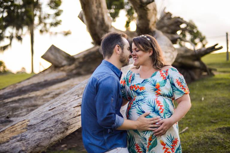 Ensaio de gestante fotografado pelo melhor fotógrafo de ensaios de campo largo e Curitiba. Casal encostado no tronco de árvore com as mãos na barriga