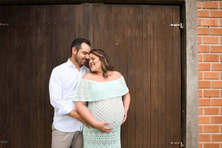 Ensaio de gestante fotografado pelo melhor fotógrafo de ensaios de campo largo e Curitiba. Gestante e marido em frente à porta de madeira