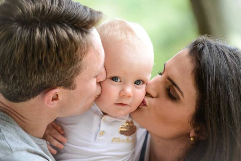 Família feliz, pai, mãe e filha fotografados pelo melhor fotógrafo de Curitiba e Campo Largo, Michel Druziki. Pais beijando a filha bebê