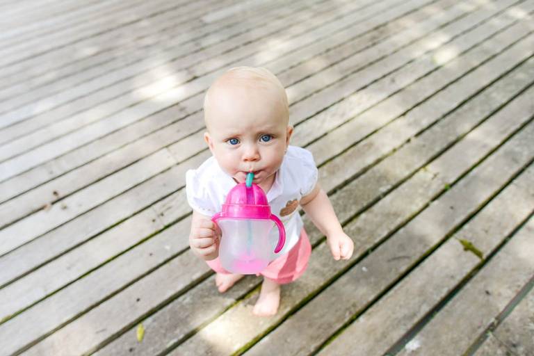 Família feliz, pai, mãe e filha fotografados pelo melhor fotógrafo de Curitiba e Campo Largo, Michel Druziki. Bebê tomando agua no copinho