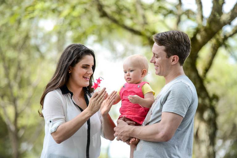 Família feliz, pai, mãe e filha fotografados pelo melhor fotógrafo de Curitiba e Campo Largo, Michel Druziki. Mãe cantando parabéns para a filha 1 aninho