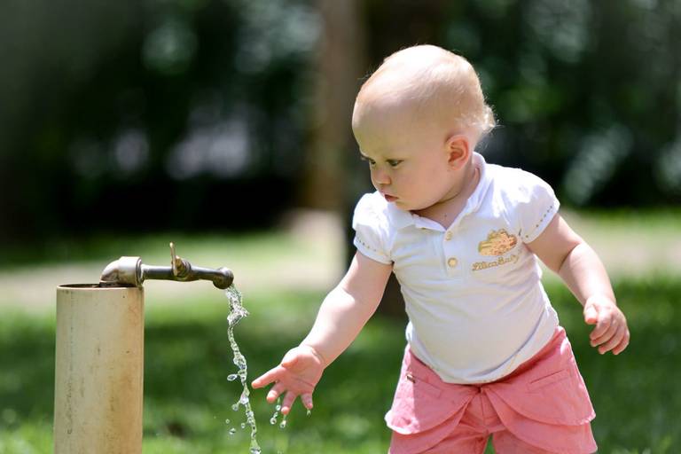 Família feliz, pai, mãe e filha fotografados pelo melhor fotógrafo de Curitiba e Campo Largo, Michel Druziki. Bebe tentando pegar agua da torneira