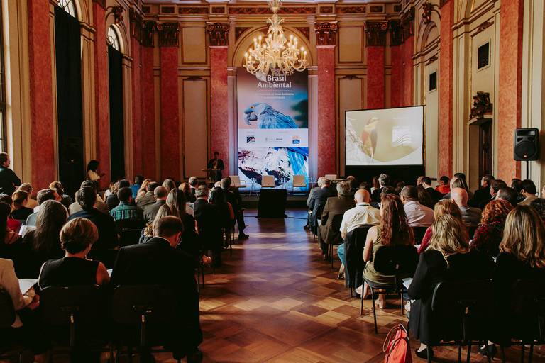 evento corporativo de palestras na casa FIRJAN em botafogo. Salão com pessoas sentadas em cadeiras diante do palco iluminado para as apresentações