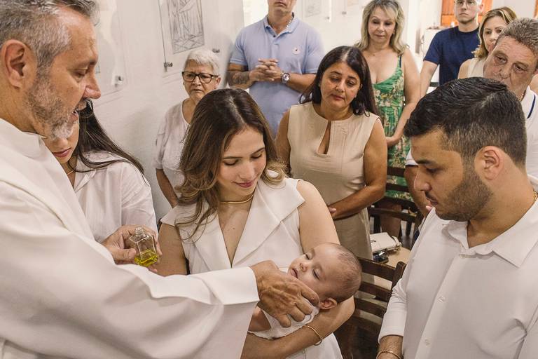 Foto de padre ungindo criança em batizado na capela São José no Swiss Park - Fotografa em SBC