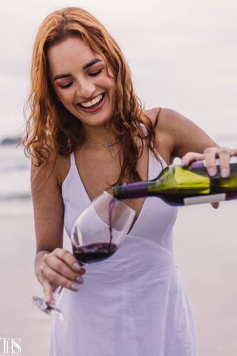 mulher colocando vinho em taça ensaio feminino praia - fotografa em sp sbc