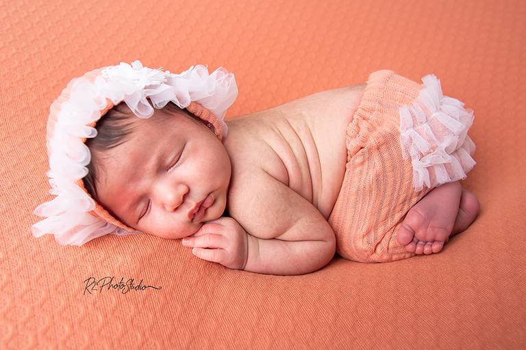 Foto de bebe de gorrinho e calça salmão de bumbum para cima