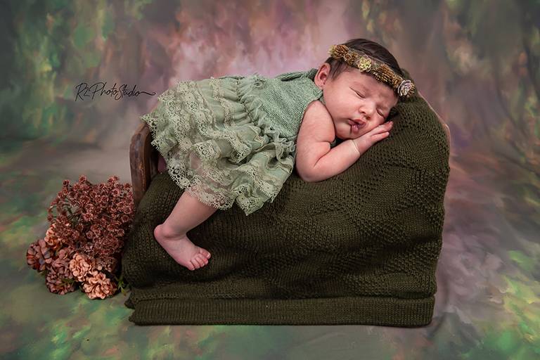 Foto de bebe com vestido verde deitada na caminha