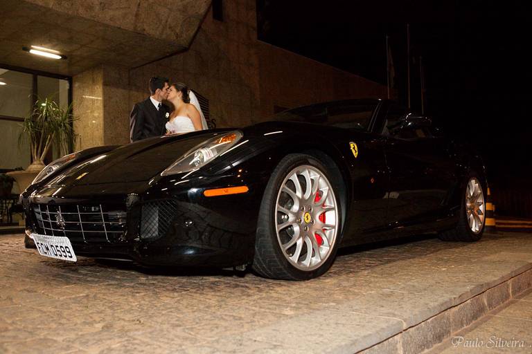 Noivos se beijando ao lado de Ferrari preta