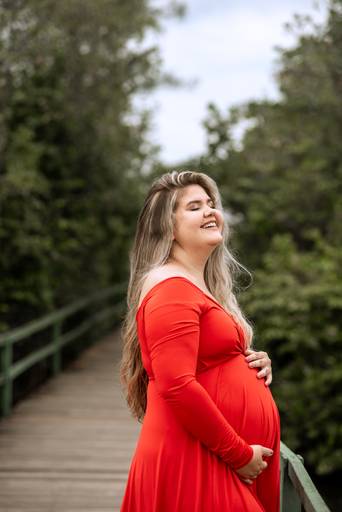 Gestante linda de vestido vermelho no lago 
