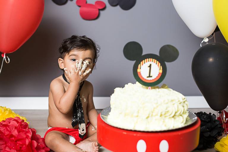 Bebe-mandando-beijo-com-mao-suja-de-bolo-em-ensaio-de-smash-the-cake