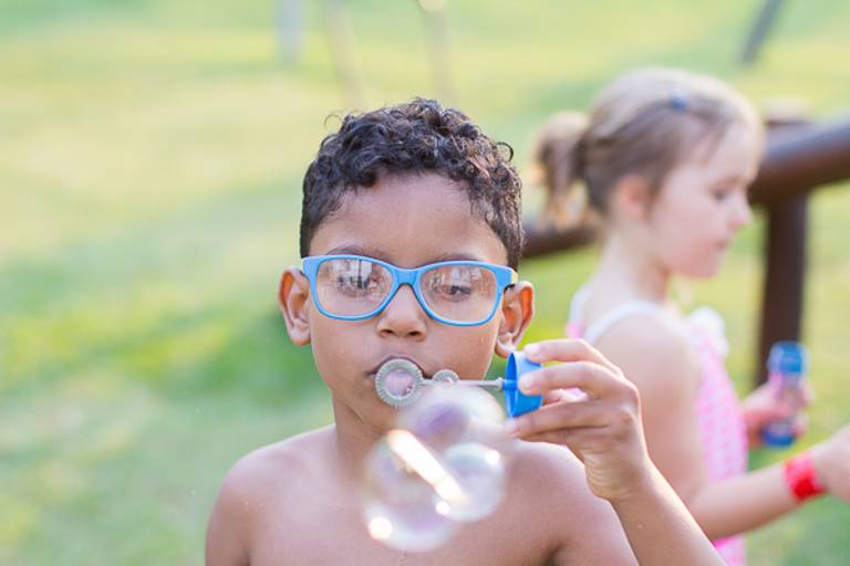 Garoto-fazendo-bolhinhas-de-sabão-com-óculos-azul-em-campinas