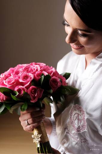noiva segurando e olhando o buque de rosas 
