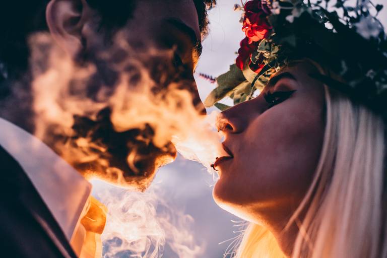 Novios al atardecer en el campo. Sol de la tarde. Humo. Pareja de novios en la sesión de fotografía de Erika Fayolle. Casamiento en Rosario y Buenos Aires.