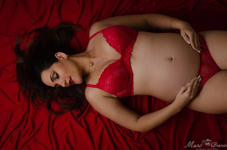 Fotografia de gestante de calcinha,  sutiã e tecido vermelhos em estúdio