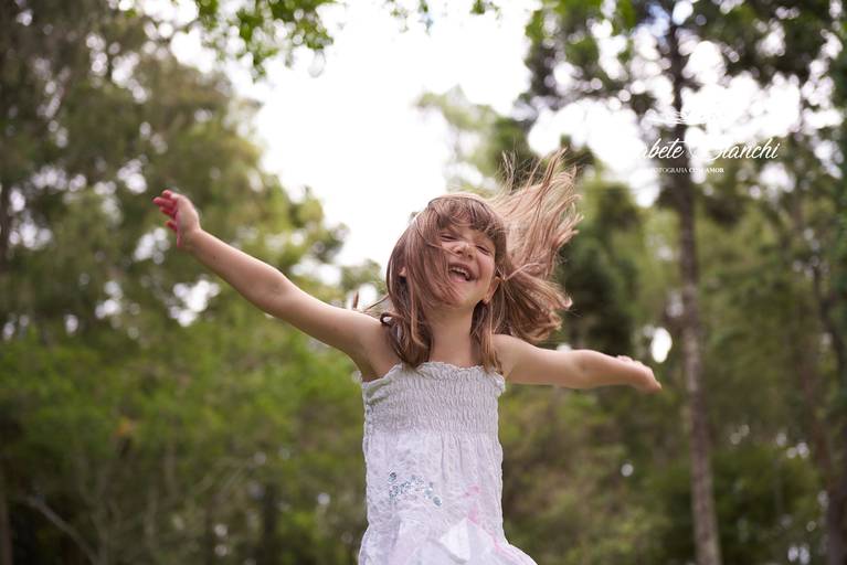 Crianças com braços abertos, feliz e curtindo a liberdade de movimentos em ensaio infantil externo, em Caxias do Sul.