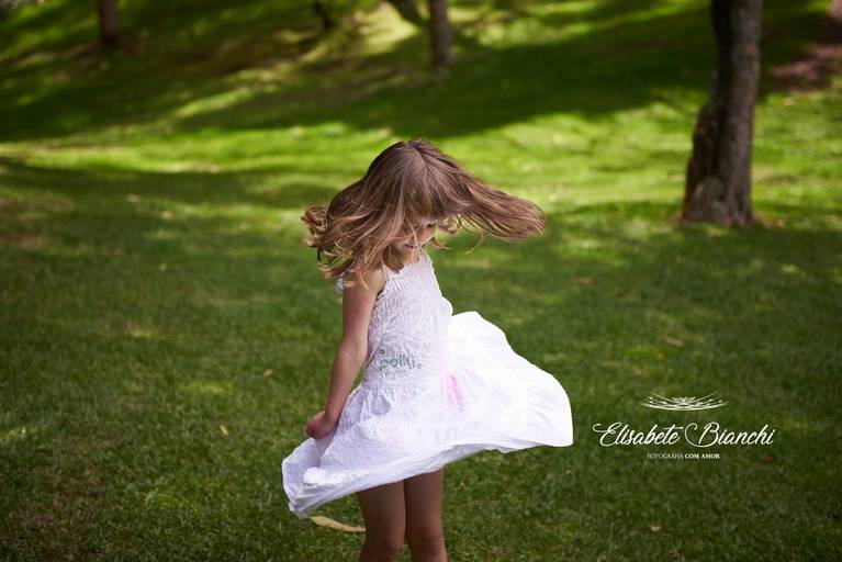 Criança rodando o vestido e o cabelo, em ensaio infantil externo, em Caxias do Sul