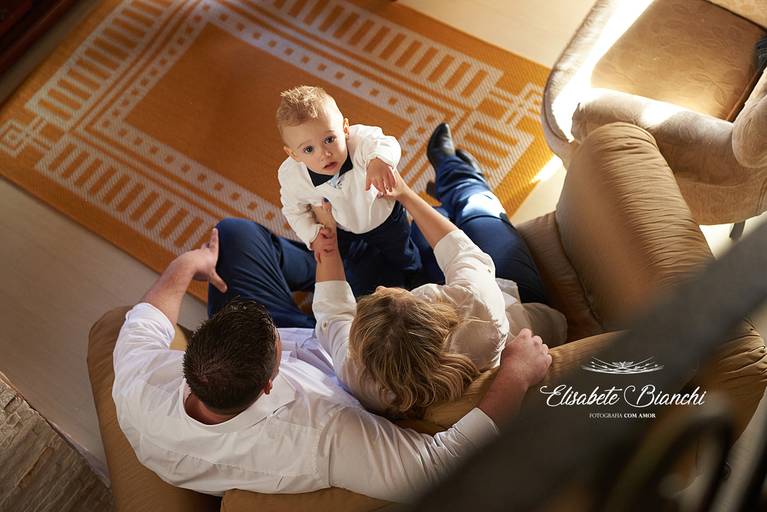 Família no sofá, com criança no colo da mãe, ângulo aéreo, em ensaio infantil lifestyle, em Caxias do Sul. 