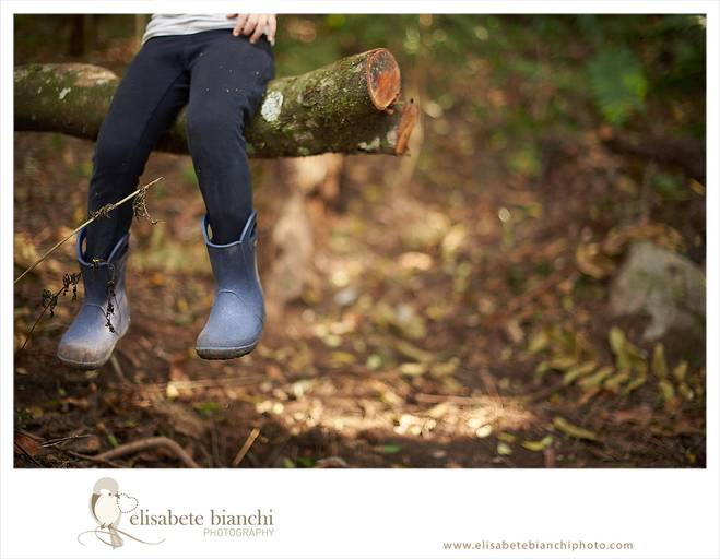 Foto detalhe de pernas de criança com galocha, sentada em um galho de árvore, em ensaio infantil externo, entre Caxias do Sul e Farroupilha.