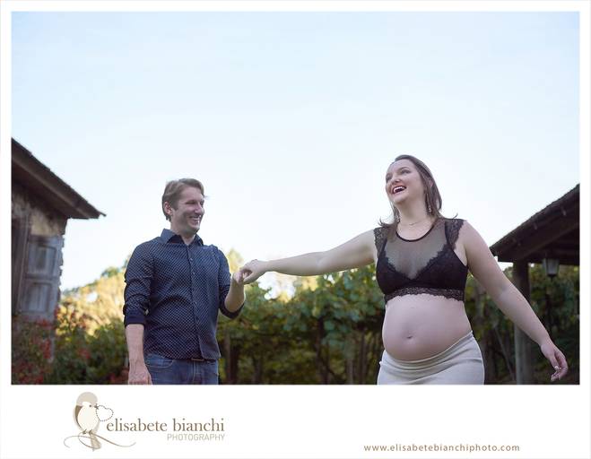 Gestante dançando feliz, junto de seu esposo, comemorando a breve chegada da filha, em ensaio externo de fotos da gestação, realizado nas Casas Bonnet, no interior de Caxias do Sul.