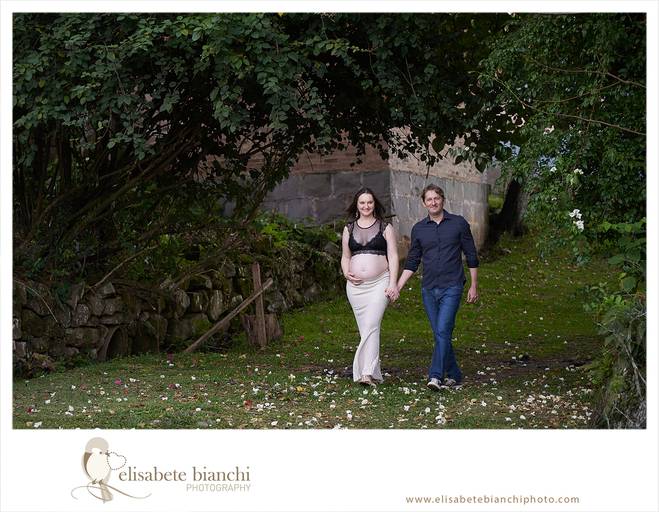 Casal gestante caminha em direção à câmera. A fotografia faz parte do ensaio externo da gestação, realizado nas Casas Bonnet, no interior de Caxias do Sul. 