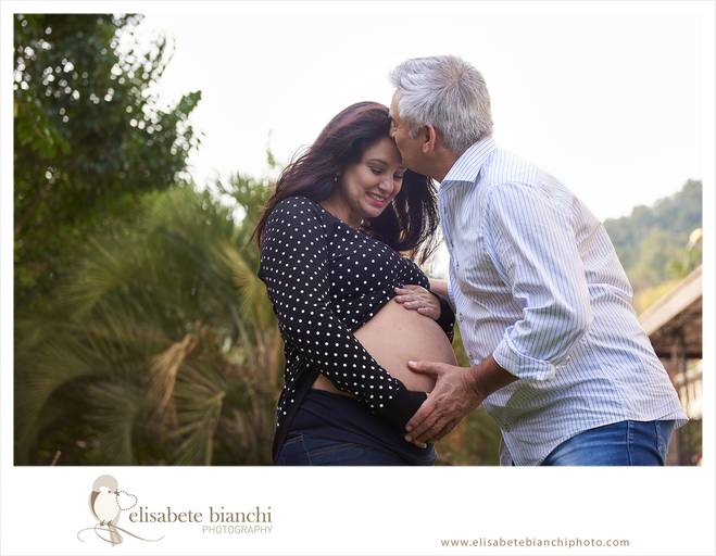  Casal gestante feliz com a gestação, onde o pai beija a testa da mãe, em ensaio fotográfico externo, em Galópolis, Caxias do Sul.