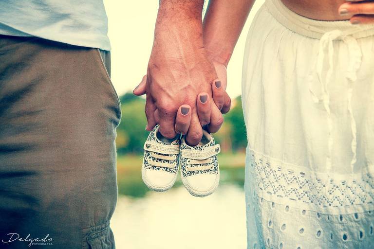 gestante e marido segurando sapatinho do bebê