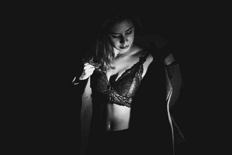 Foto de ensaio sensual preto e branco em local externo de mulher branca vestindo sutiã, saia e sobretudo.