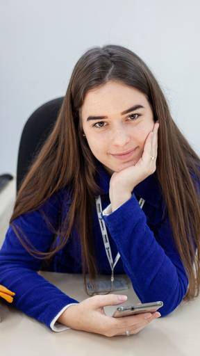 retrato de garota branca de cabelo castanho sentada e apoiando a cabeça em sua mão
