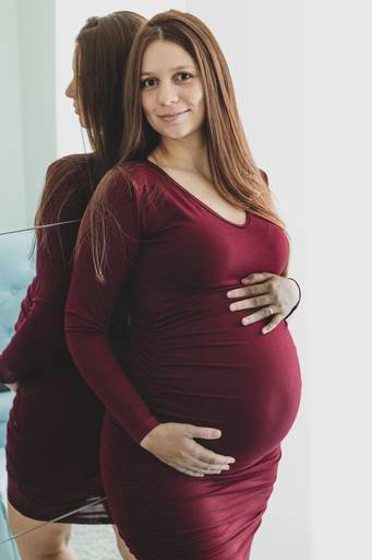 Gestante em pé encostada no espelho do armário do quarto