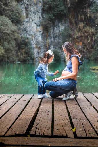 menina brincando com barriga da mãe grávida