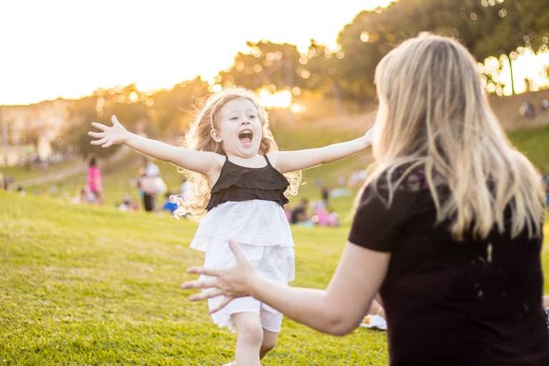  filha correndo para abraçar a mãe no Parque ao pôr do sol 