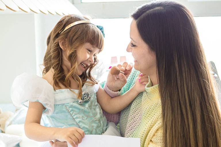mãe e filha vestida de princesa brincando  e sorrindo
