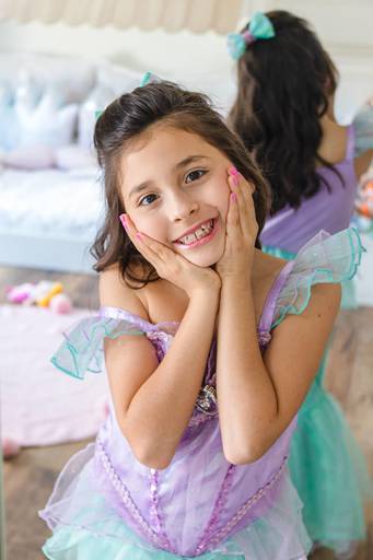 menina vestida de princesa Ariel fazendo pose e sorrindo para a foto
