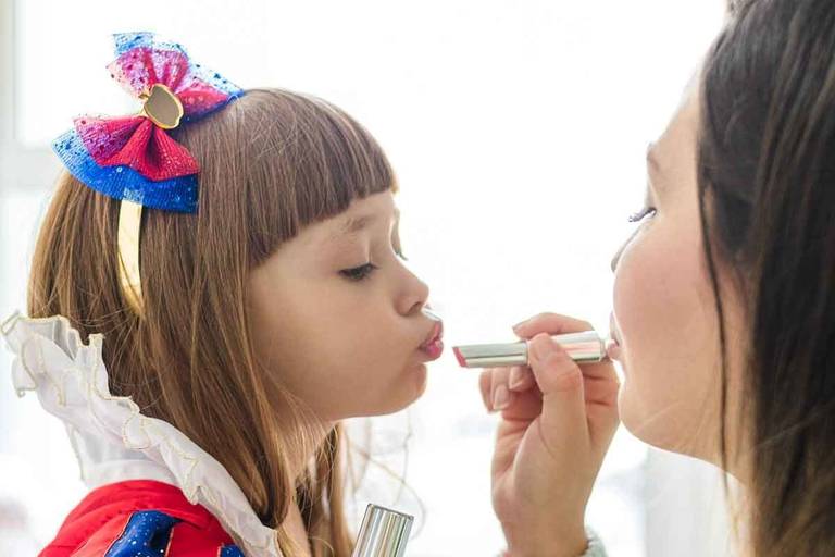 mãe passando batom na filha, menina fazendo bico com fantasia da Branca de Neve