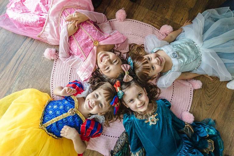 meninas deitadas no chão com fantasia de princesas