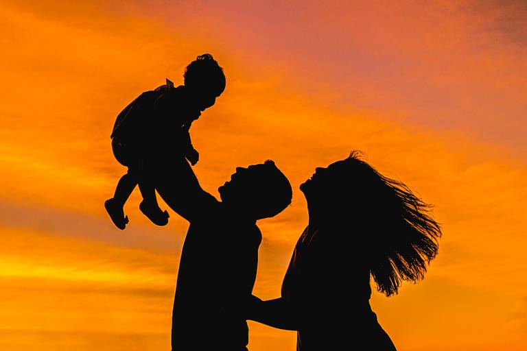 Pai e Mãe levantando filha no alto no Parque Lago Azul em Curitiba ao pôr do sol 