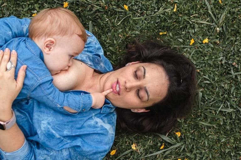 mãe amamentando bebê deitada na grama no parque Barigui em Curitiba